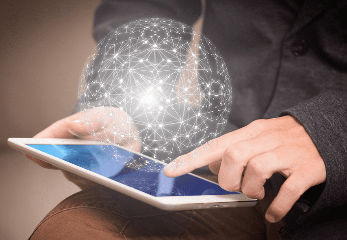 A person using a tablet with a sphere of light in the background.